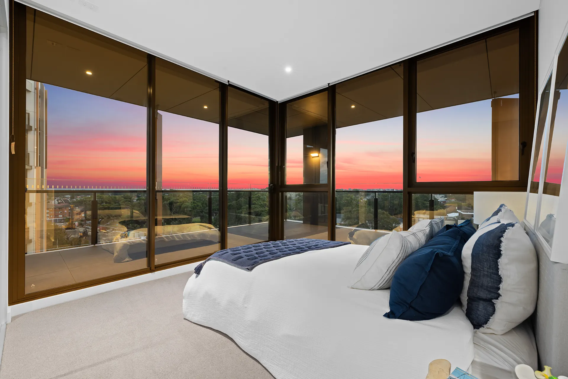 Bedroom with floor-to-ceiling windows and sunset outlook